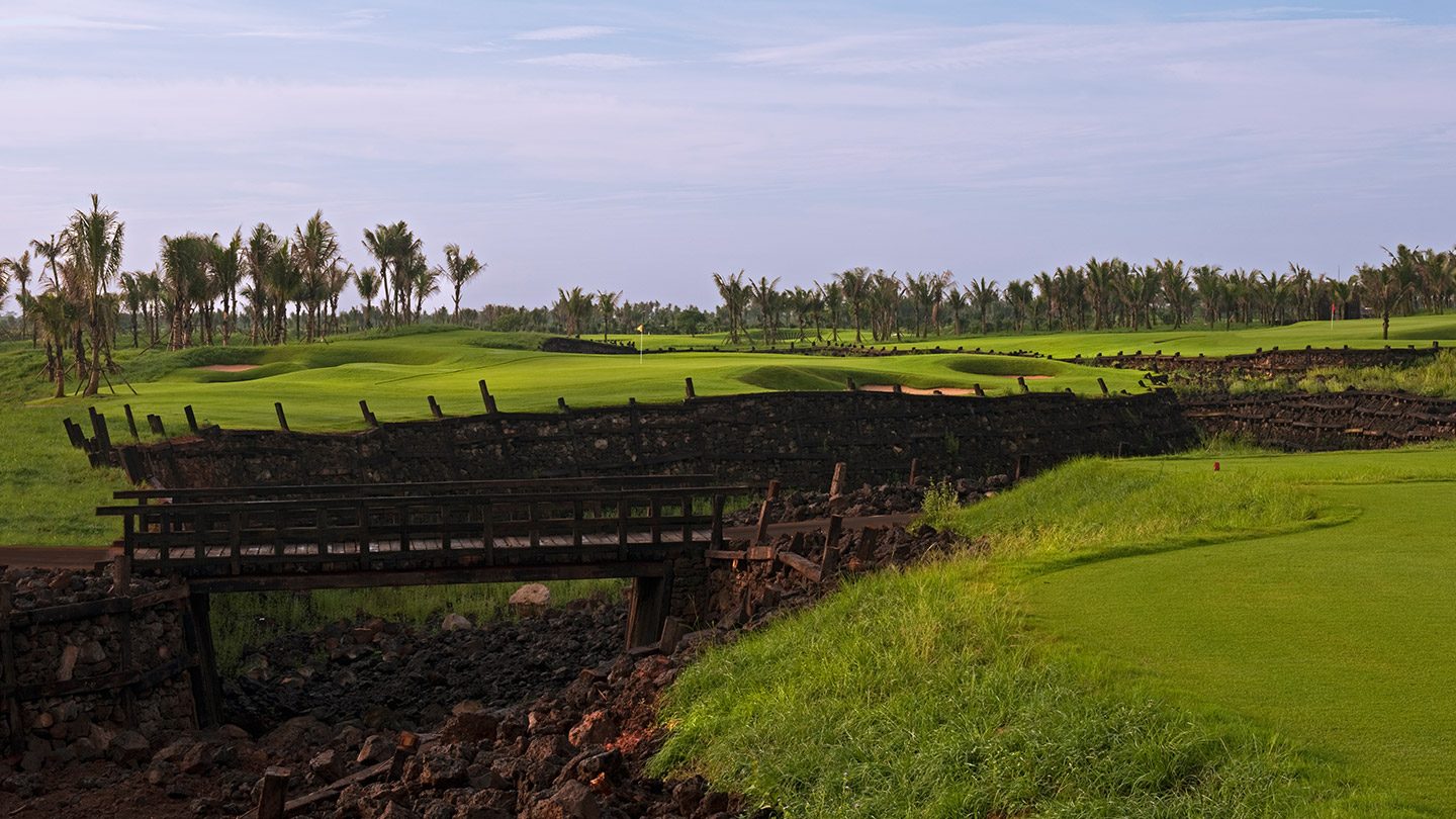 A wall of black volcanic rock crossing the fairway toward a green at Blackstone