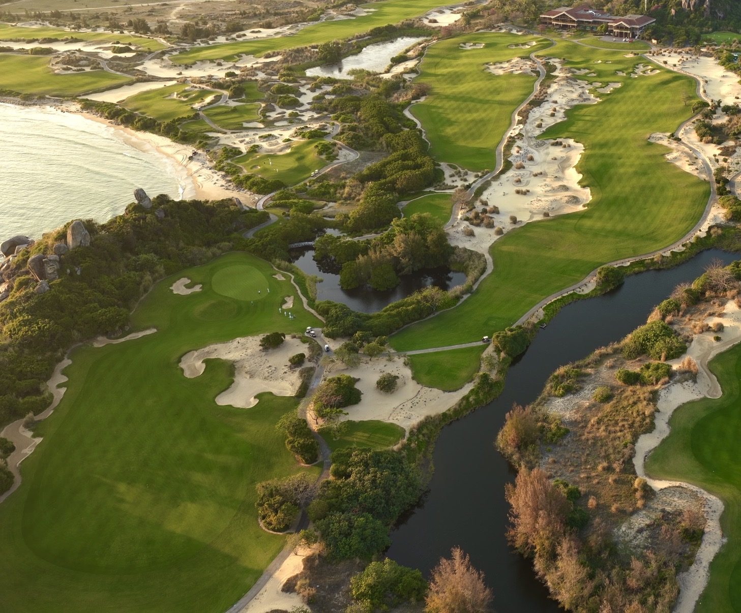 An aerial of The Dunes fairways, water and sand winding toward the sea at Shenzhou Peninsula
