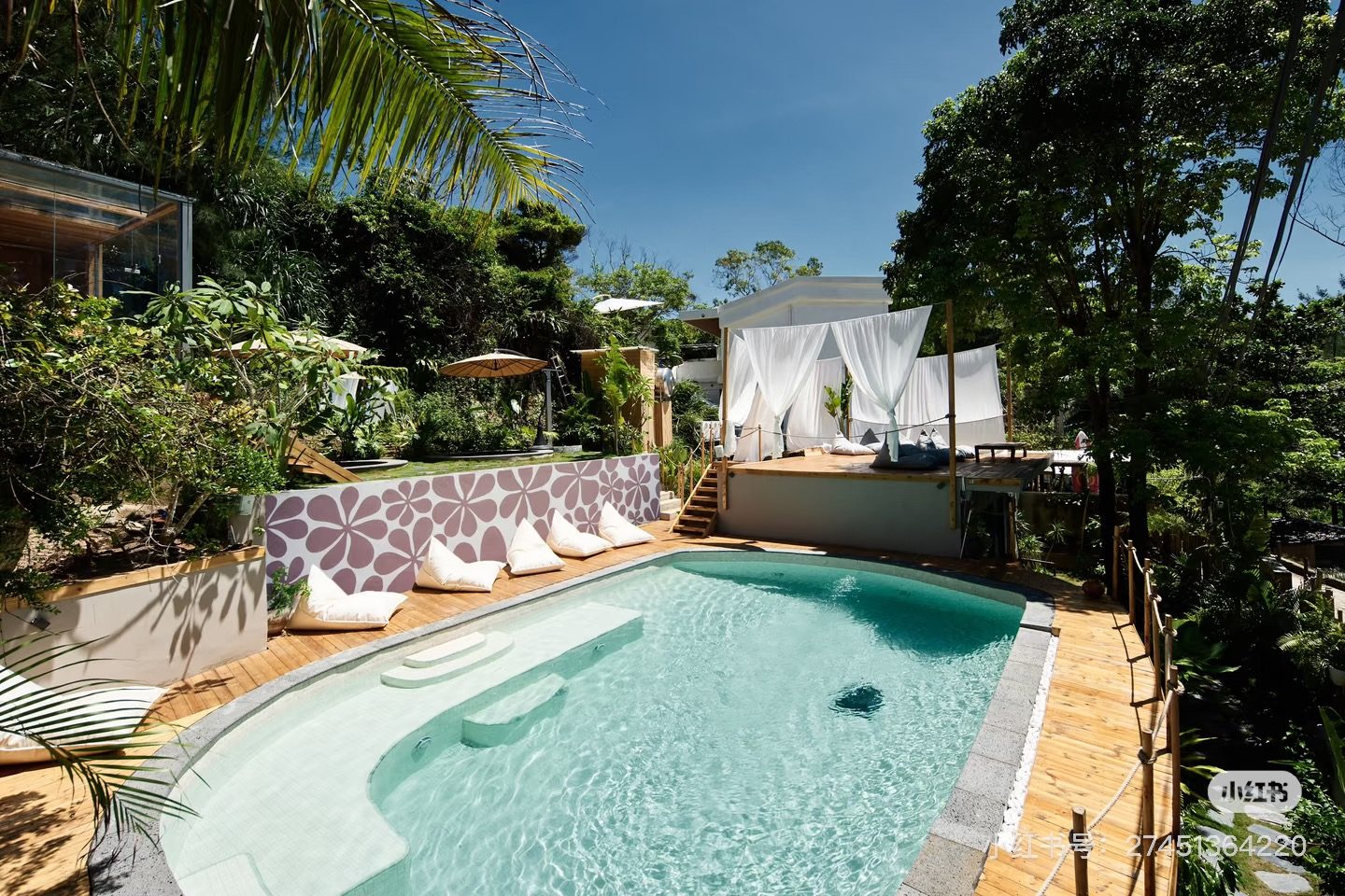 Recovery pool with white daybeds under tropical trees near the Riyue Bay wave pool, Wanning, Hainan — book a wave pool surf trip with recovery built in